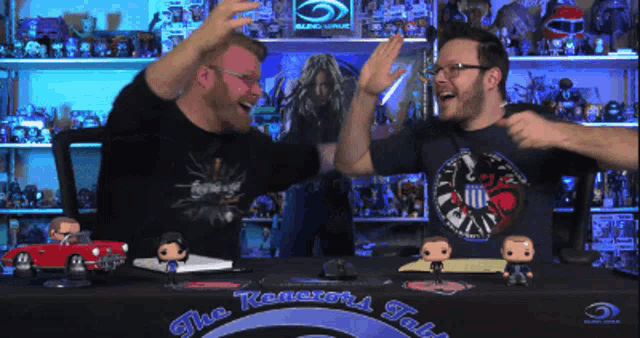 two men giving each other a high five in front of a table that says the renegade talks