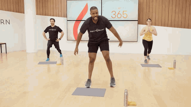 a man wearing a shirt that says body burn is jumping in a gym