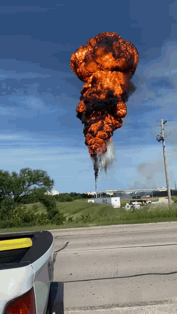 a truck is parked in front of a large explosion with smoke coming out of the ground