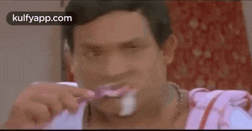 a man is brushing his teeth with a toothbrush and smiling .
