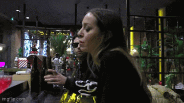 a woman is sitting at a table with a bottle of beer on it