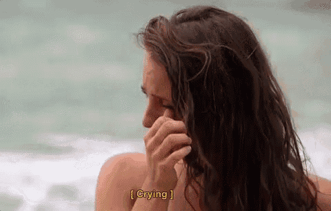 a woman is crying on the beach while covering her face .