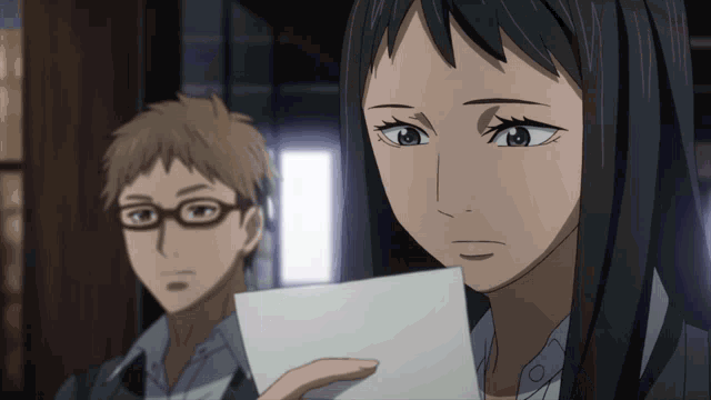 a woman is holding a piece of paper in front of a man