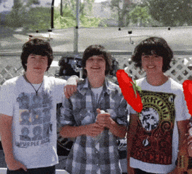 three boys are posing for a picture and one of them has a shirt that says purple