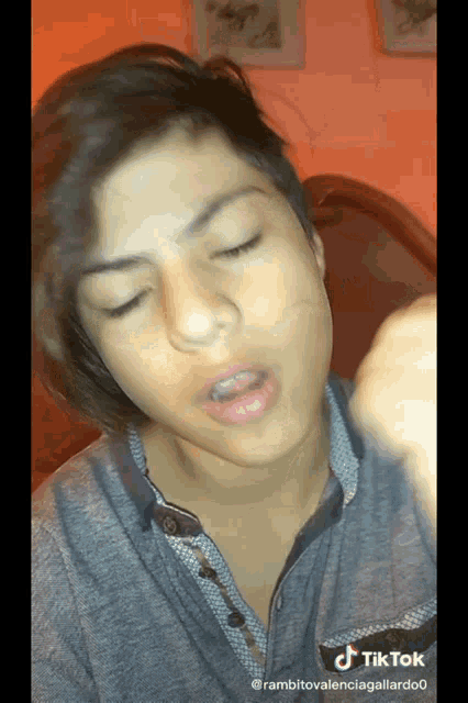 a tiktok video of a young man with his eyes closed and a gray shirt