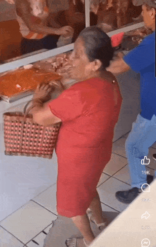 a woman in a red dress is holding a basket in front of a man