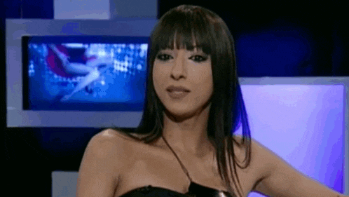 a woman with long hair and bangs is sitting in front of a television .