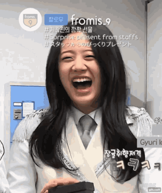 a woman is laughing in front of a sign that says fromis_9
