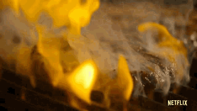 a close up of a steak being cooked on a grill with flames coming out of it .
