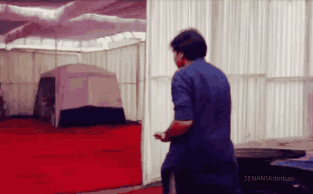 a man in a blue shirt is standing in front of a white tent with the words senaniafilmmaker on the bottom