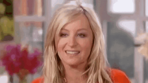 a woman is smiling and looking at the camera while wearing a red shirt .
