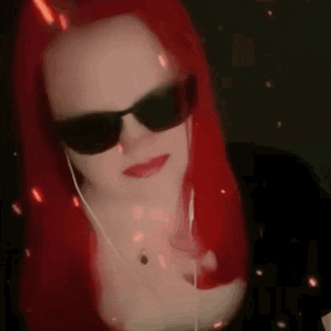 a woman with red hair and sunglasses is wearing headphones and a necklace .