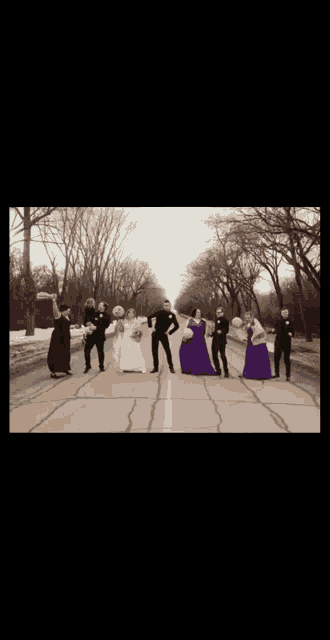 a bride and groom pose with their wedding party on the side of the road