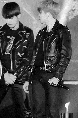 a man in a leather jacket is holding a microphone and standing next to another man in a leather jacket .