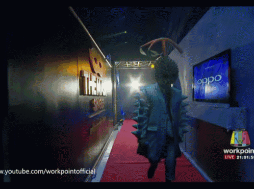 a person in a costume walks down a red carpet in front of an oppo television