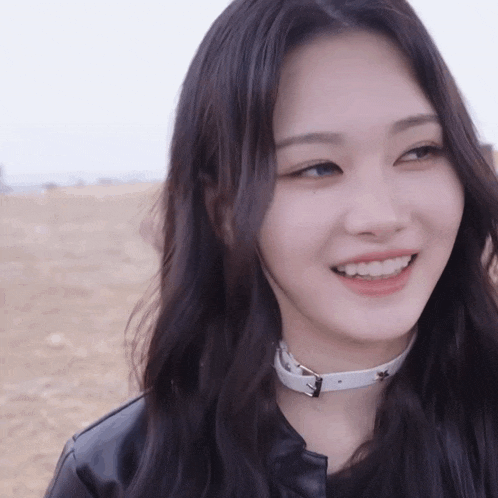 a woman wearing a white choker and a leather jacket smiles