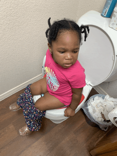 a little girl sits on a toilet with her pants down
