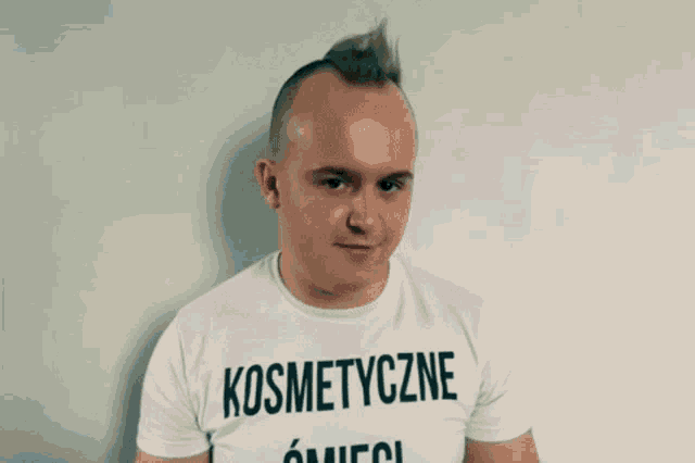 a man with a mohawk wears a white t-shirt that says kosmetyczne