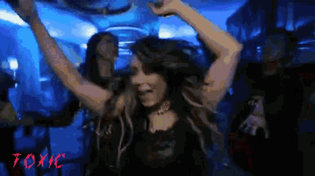 a woman is dancing in a dark room with toxic written on the bottom right