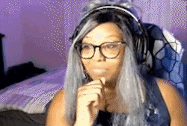 a woman wearing headphones and glasses is sitting on a bed