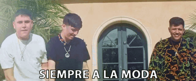 three men are standing in front of a building with the words siempre a la moda written on the bottom