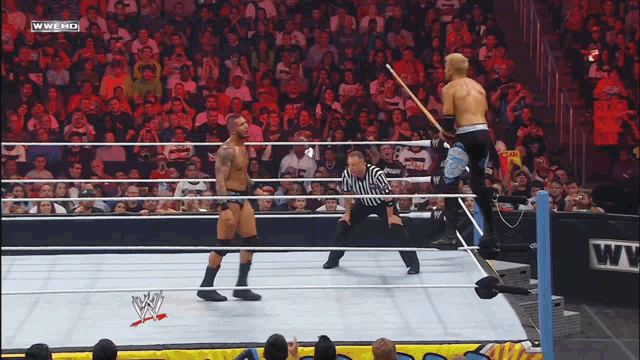 two wrestlers in a wrestling ring with a referee and a wwe logo