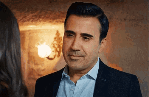 a man in a suit and a blue shirt is looking at a woman .