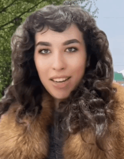 a woman with curly hair wearing a fur coat is smiling