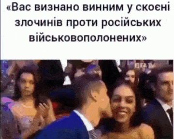 a man kissing a woman on the cheek in front of a crowd of people .