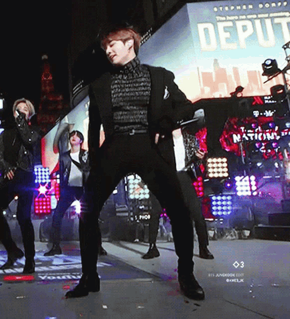 a man in a suit is dancing on a stage in front of a large screen that says deputy