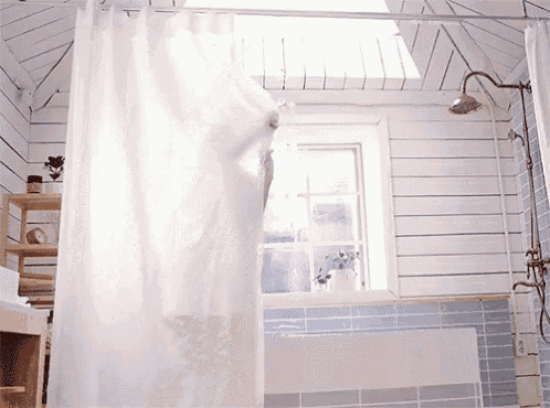 a white shower curtain is hanging in a bathroom