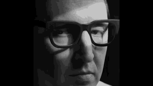 a close up of a man 's face with glasses on