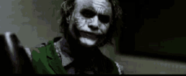 a close up of the joker from the movie the dark knight rises with blood on his face .