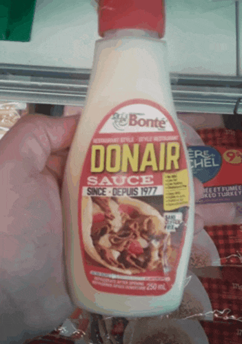 a bottle of donair sauce is being held by a person