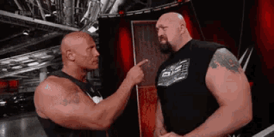 two wrestlers are standing next to each other and one is pointing at the other