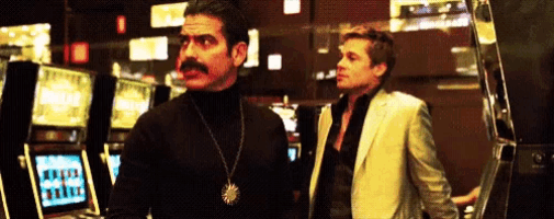 a man with a mustache is standing next to another man in a casino