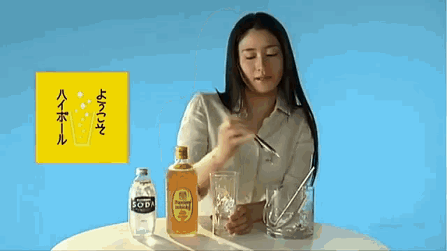a woman sits at a table with a bottle of suntory whisky and a bottle of soda