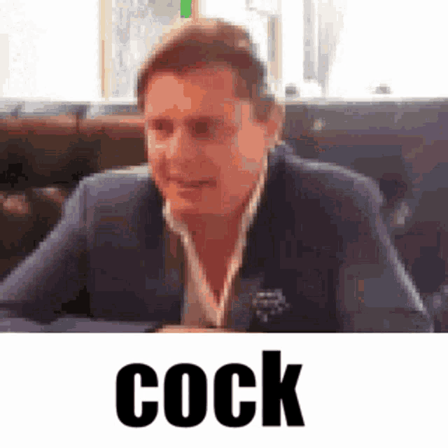a man in a suit and tie is sitting at a table with the word cock written above him .