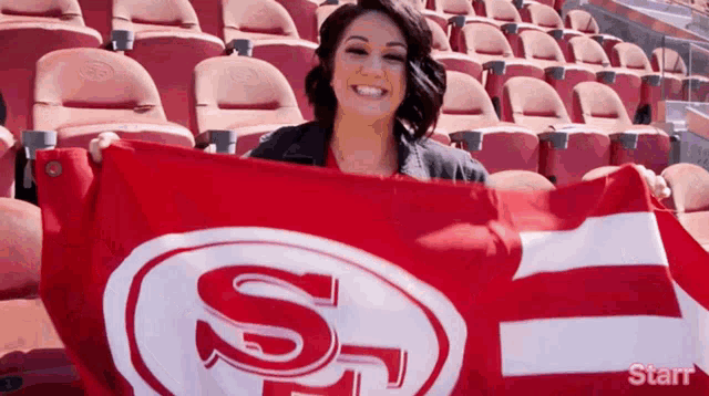 a woman is holding a flag with the letter s on it in a stadium
