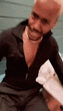 a man wearing a choker and a black shirt is sitting on a table .