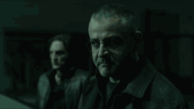a man is looking at himself in a mirror in a dark room .