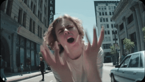 a young man is screaming in front of a building that says lbarc