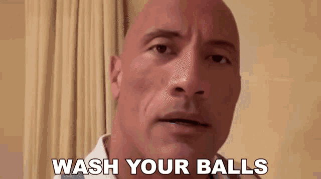 a bald man says " wash your balls " in front of a curtain