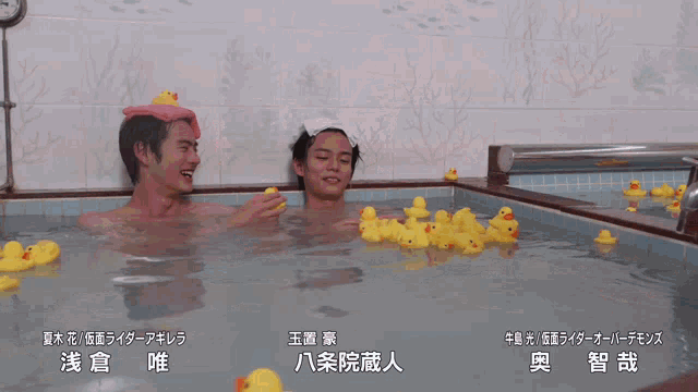 two women are playing with rubber ducks in a bathtub with chinese writing on the bottom