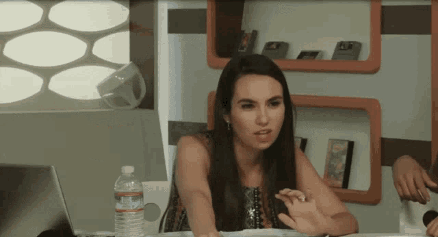 a woman sitting at a table with a bottle of aquafina water in front of her