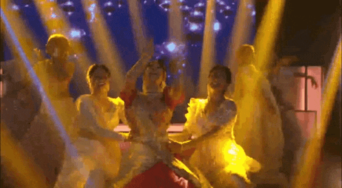 a group of dancers are dancing on a stage in front of a blue background .