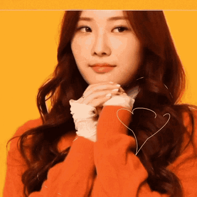 a woman wearing an orange sweater has a heart drawn on her hair