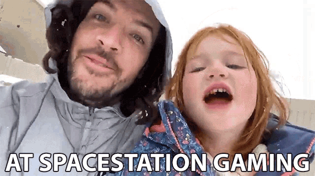 a man and a little girl are posing for a picture with the words " at spacestation gaming " behind them