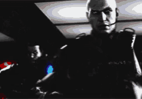 a black and white photo of a man with a headset on holding a gun .