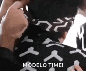 a close up of a person holding a piece of paper that says modelo time on it .